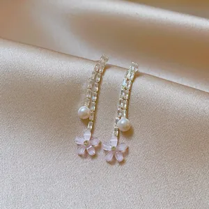 Close-up detail of elegant fringe earrings featuring pearls and pink crystal flower petals