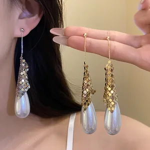 Elegant water drop pearl earrings with gold and silver mesh detail on a model.