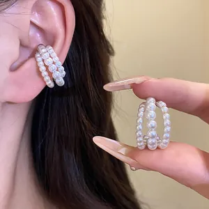 Detail view of a vintage three-layer pearl beaded ear cuff shown on ear and in hand.