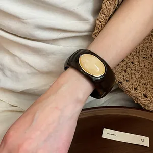 Detailed view of a retro acrylic oval bangle with marble effect stone inlay on a wrist