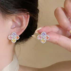 Gros plan détaillé de boucles d'oreilles fleurs en zircon multicolore portées et tenues.