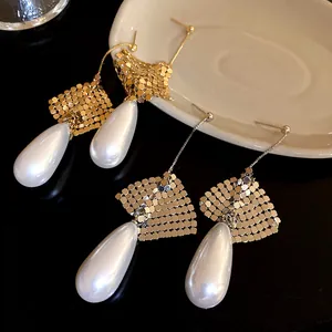 Elegant detailed view of pearl drop earrings with golden metallic mesh and silver needles