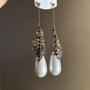 Detail view of elegant silver drop earrings with metallic mesh and large white pearls