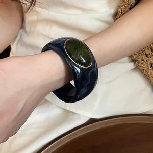 Close-up view of a vintage acrylic marbled bangle bracelet featuring a green oval stone