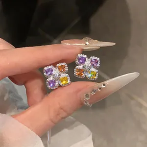 Gros plan de boucles d'oreilles fleurs en zircon avec des pierres violettes et jaunes