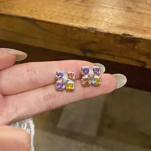 Détail de boucles d'oreilles fleur en zircon coloré avec des pierres carrées violettes et jaunes