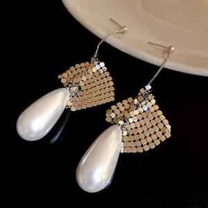 Close-up view of elegant silver teardrop pearl earrings with unique golden mesh detail