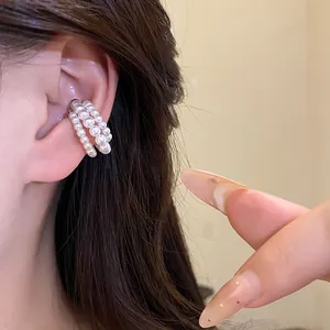 Detail view of a vintage three-layer pearl beaded ear cuff worn on an ear