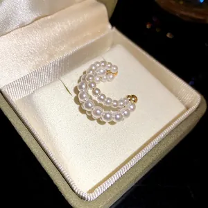Close-up of elegant three-layered white pearl ear cuff inside a luxury cream jewelry box