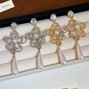 Detail of 18k gold plated flower earrings with crystals and teardrop pearls