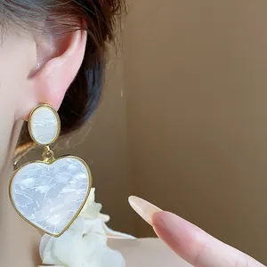 Detailed macro shot of elegant resin heart pendant earrings with gold-toned plating