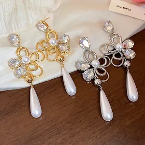 Close-up of elegant flower earrings with crystals and teardrop pearls in gold and silver