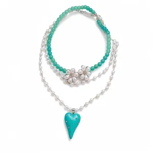 Elegant layered pearl necklace featuring green beads, diamond flowers, and a resin heart pendant