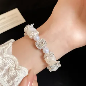Dettaglio macro di un romantico bracciale in stile francese con perle e ciondoli di cristallo.