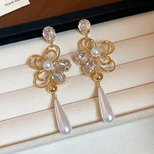 Detail view of 18k gold-plated floral earrings with crystal accents and pearl drops