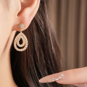Nahaufnahme eleganter, 18 Karat vergoldeter Tropfenohrringe mit glitzernden Zirkonsteinen