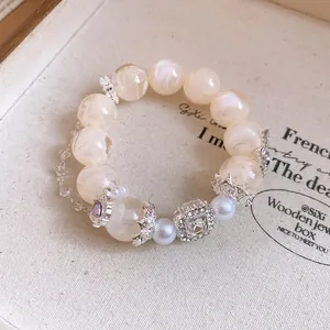 Primo piano di un bracciale romantico con perle crema e un cristallo quadrato fine.