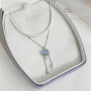 Double-layer pearl necklace with a blue cloud pendant and star tassel details.