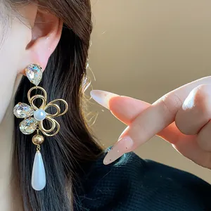 Detailed shot of 18k gold plated flower earrings with crystals and drop pearls
