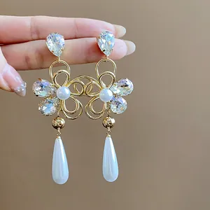 Detail shot of 18k gold plated flower earrings with rhinestones and elegant pearl drops