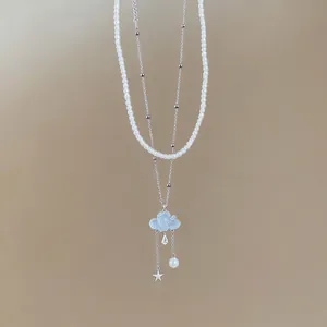 Elegant layered necklace with pearl beads, blue cloud pendant, and star tassel detail