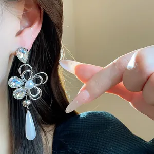 Close-up of elegant flower earring with pearls and sparkling rhinestones worn on ear