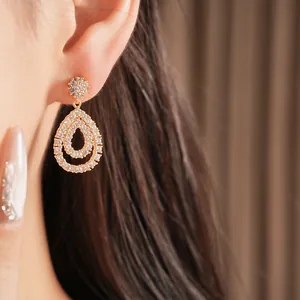 Nahaufnahme von 18K vergoldeten Tropfenohrringen mit glitzernden Zirkonia an einem Model.