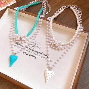 Detailed view of layered pearl beaded necklaces with resin heart pendants and flowers