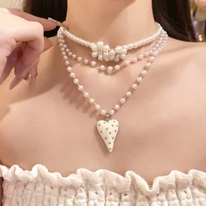 Close-up of pearl beaded layered necklace with heart pendant and flower accents