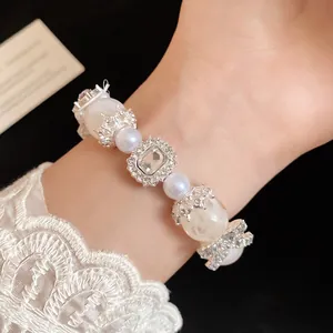 Dettaglio di un elegante braccialetto di perle e cristalli stile francese su polso in pizzo