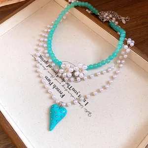 Macro view of multi-layered pearl necklace with teal heart pendant and flower charms