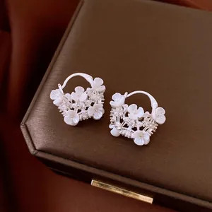 Elegant white flower hoop earrings with pearls and rhinestones on a jewelry box display