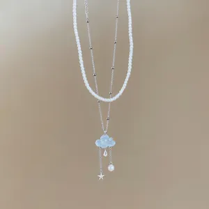 Detail view of layered necklace featuring blue cloud, star, and pearl charms