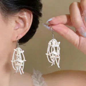 Detailed macro view of elegant white shell and bead tassel earrings worn by an Asian model