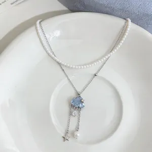 Detailed macro shot of a layered necklace featuring a blue cloud and star tassel