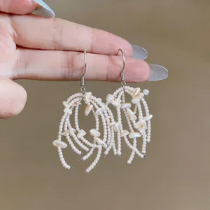 Detailed close-up showing the intricate shell pieces and white beads on tassel hook earrings
