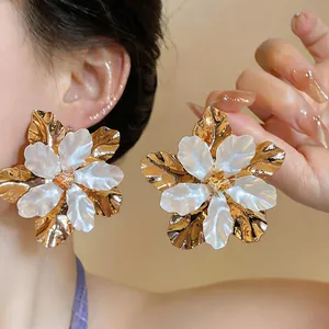 Detailed view of elegant gold and white layered petal flower stud earrings on model