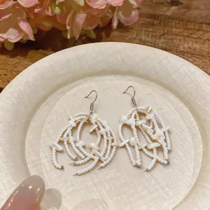 Macro view of white shell beaded tassel earrings on a textured decorative plate