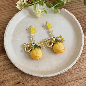 Handmade yellow rose floral drop earrings with exquisite beadwork on ceramic plate
