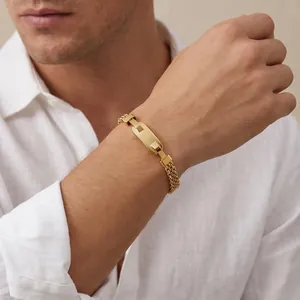 Detail of a gold stainless steel mesh bracelet with a polished engravable plate on wrist.