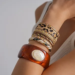 Gros plan sur un ensemble de bracelets en cuir léopard et un jonc en résine ambre