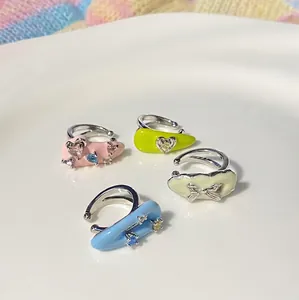 Close-up of four colorful ear cuffs with heart and bow details on a white surface