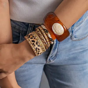Détail d'un bracelet en cuir léopard et d'un jonc en résine ambre sur le poignet