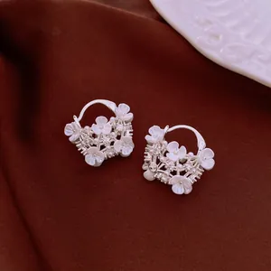 Macro shot of silver hoop earrings featuring delicate white flowers and small pearls