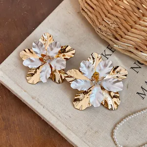 Detailed view of elegant gold metal flower earrings featuring white enamel petals texture