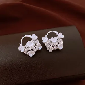 Detailed close-up view of silver hoop earrings decorated with white flowers and pearls