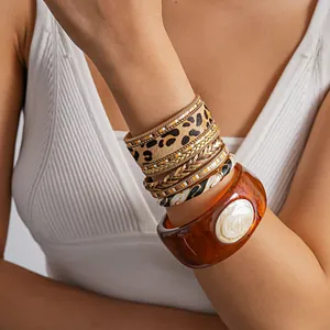 Vue détaillée des bracelets en cuir léopard et du jonc en résine ambrée sur le poignet