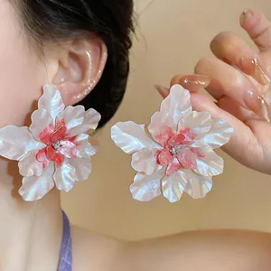 Macro detail view of exaggerated white and pink drip oil floral earrings with center rhinestone.