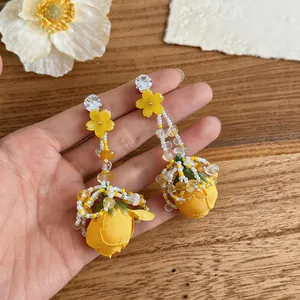Close-up detail of exquisite yellow rose tassel earrings with beadwork and shiny rhinestones.