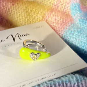 Close-up of a neon yellow enamel ear cuff featuring a delicate silver heart with a yellow stone.